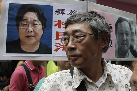 Hong Kong bookseller Lam Wing-kee stands next to a placard with picture of missing bookseller Gui Minhai (File | AP)