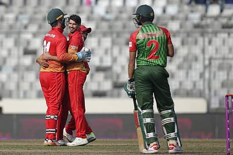Zimbabwe's captain Graeme Cremer, second left, celebrate with his teammate Sikandar Raza, second right, and wicketkeeper Brendan Taylor, left, the dismissal of Bangladesh's captain Mashrafe Mortaza, right, during the Tri-Nation one-day international crick