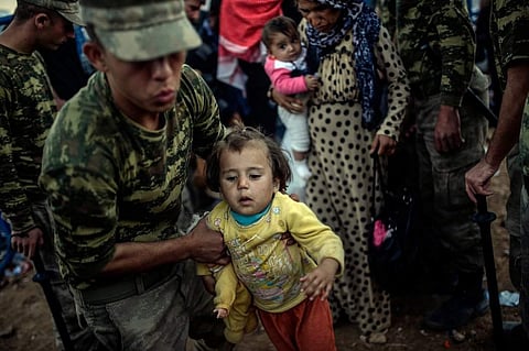 Turkish soldiers helping Kurdish families fleeing the fighting in Syria.  (Photo | Associated Press)