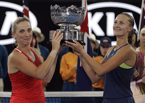 Hungary's Timea Babos, left, and partner France's Kristina Mladenovic embrace as they pose for a photo with their trophy after they defeated Russia's Ekaterina Makarova and Elena Vesnina in the women's doubles final at the Australian Open tennis champions