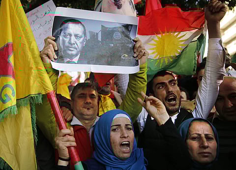 Kurdish demonstrators holding Kurdish flags and a picture of the Turkish president protest against the operation by the Turkish army (File | AP)