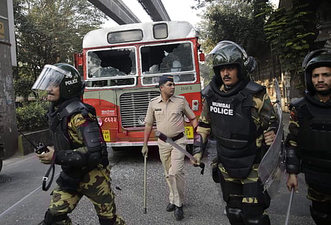 Policemen patrol near a bus damaged during a protest by Dalit groups in Mumbai on Tuesday . (AP)