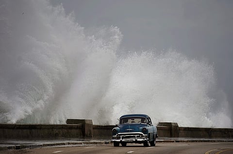 Waves crash against the Malecon, triggered by the outer bands of Hurricane Michael, as man drives past in a classic American car in Havana, Cuba, Oct. 9, 2018. (Photo | AP)