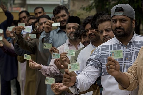 Pakistani voters display their ID cards while waiting in the queue to cast their votes. (File photo | PTI)