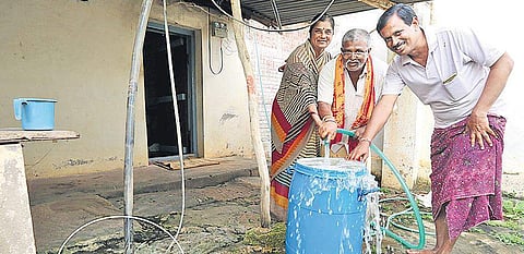 B S Parameshwarappa and his wife along with farmer Bheemarao collect hot water from the borewell in the backyard of his house | Shimoga Nandan
