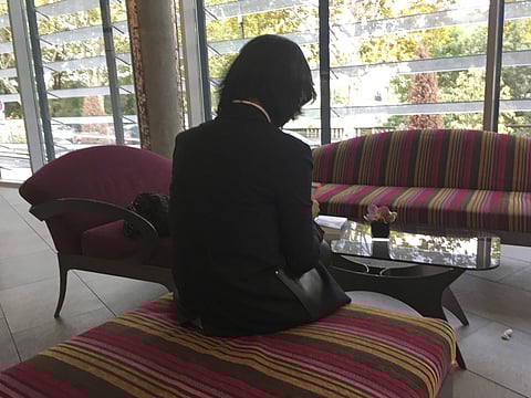 A file photo of Grace Meng, the wife of missing Interpol President Meng Hongwei, who does not want her face shown, consults her mobile phone in the lobby of a hotel in Lyon, central France, where the police agency is based. (Photo | AP)