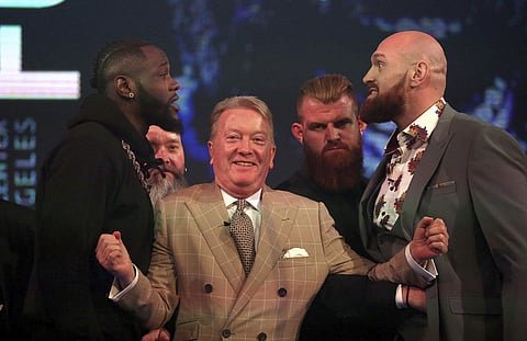 Deontay Wilder, left, and Tyson Fury, right, are kept apart by promoter Frank Warren during a press conference at BT Sport Studio, London. | AP