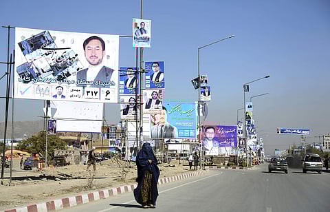 Campaign posters for parliamentary candidate are displayed over a street for the upcoming election, as a woman waits for transportation in Kabul, Afghanistan. (File Photo | AP)