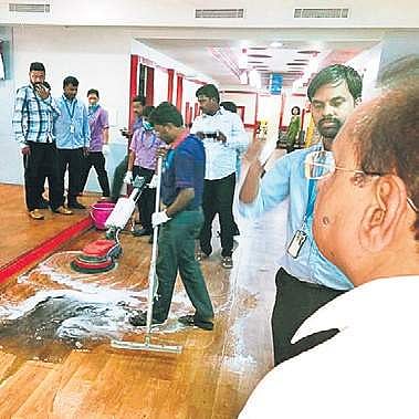 KSPCB chairman watches as RxDx hospital staff clean the black soot accumulated on the floor of the hospital (Photo | Express)