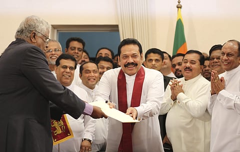 Sri Lanka's newly appointed prime minister Mahinda Rajapaksa, center, hands over inaugural documents to an official during his duties assuming ceremony in Colombo | AP