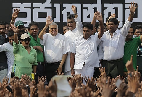 Sri Lanka's sacked prime minister Ranil Wickremesinghe, third from left in white shirt and black trousers, waves to his supporters along with law makers supporting him during a protest rally outside the prime ministers official residence in Colombo | AP