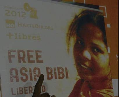 Ashiq Masih, husband of Asia Bibi, a Christian woman facing death sentence for blasphemy, points to a poster bearing an image of his wife Asia at a living area in Lahore.(File|AFP)