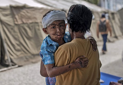 A boy injured during the tsunami is carried by his relative at a makeshift hospital in Palu, Central Sulawesi, Indonesia. (Photo| AP)