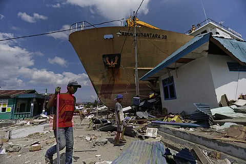 In this Thursday, Oct. 4, 2018, photo, Indonesian youths walk past Sabuk Nusantara 39 ship which was swept ashore by the tsunami in Wani village on the outskirt of Palu, Central Sulawesi, Indonesia. (Photo | AP)