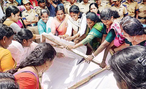 Mahila Morcha activists tearing up the flex board of Chief Minister Pinarayi Vijayan into pieces in front of the TDB office in Thiruvananthapuram. (Vincent Pulickal | EPS)