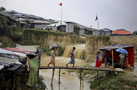 Sewer water flows in the back as Rohingya refugees cross a makeshift bamboo bridge at Kutupalong refugee camp, Bangladesh. (Photo | AP)