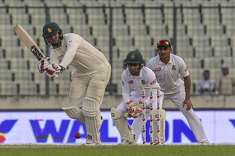Zimbabwe's cricketer Brendan Taylor (L) plays a shot as the Bangladeshi cricketers Mushfiqur Rahim (C) and Ariful Haque (R) look on during the fourth day of the second Test cricket match between Bangladesh and Zimbabwe at the Sher-e-Bangla National Cricke