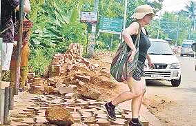 A tourist walks on the broken footpath at Kovalam Vincent Pulickal