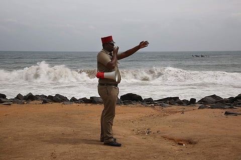 A policeman announcing over a megaphone to clear the beach area in Pondicherry. (Photo | G Pattabiraman/EPS)