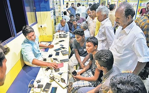 People lining up to charge mobile phones at a shop in Pattukottai on Saturday. The shop owner took no money to let people charge their phones | M K ASHOK KUMAR
