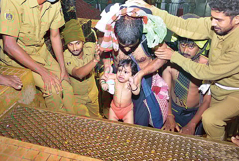 10-month-old Daksha from Kunnamkulam climbs for the first time the holy steps at Sannidhanam in Sabarimala on Wednesday. She reached Sabarimala along with her father Abhilash and sister Daitha (Photo | EPS/Manu R Mavelil)