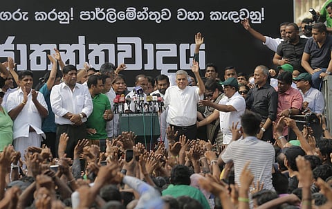 Sri Lanka's sacked prime minister Ranil Wickremesinghe (center right in white shirt and black trousers) waves to his supporters along with law makers supporting him during a protest rally outside the prime ministers official residence in Colombo (File | A