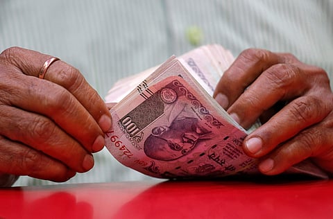 A man counts Indian currency notes inside a shop. (Photo | Reuters)