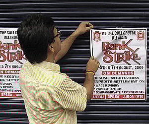 A bank employee pastes a bank strike pamphlet on the closed shutter of a bank. Image used for representational purpose only.  (Photo | Reuters)