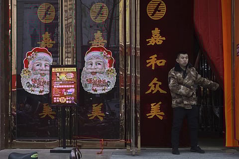 A worker guards the entrance of a shop decorated with images of Santa Claus in Zhangjiakou in northern China (Photo | AP)