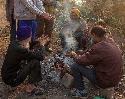People keep themselves warm around a bonfire during a cold winter morning on the outskirts of Jammu (Photo | PTI)