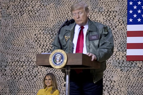 First lady Melania Trump, left, is seated on stage as President Donald Trump pauses as he speaks at a hanger rally at Al Asad Air Base, Iraq, Wednesday, Dec. 26, 2018. (Photo | AP)