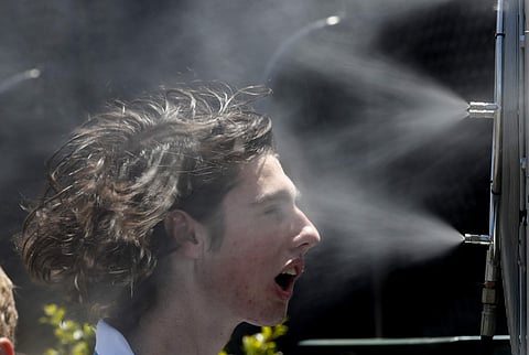 A spectator cools down in front of mist spraying fans at the Australian Open tennis championships. (File Photo | AP)
