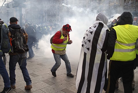 A teargas canister falls among demonstrators wearing yellow vests Saturday, Dec. 8, 2018 in Paris. (Photo: AP)