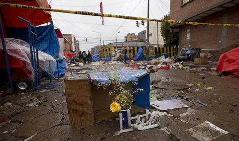 Flowers and candles sit under police tape where a gas canister exploded the previous day in Oruro, Bolivia, Sunday, Feb. 11, 2018. | AP