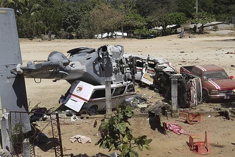 The downed helicopter lays in its side on top of a van, in Santiago Jimitepec | AP