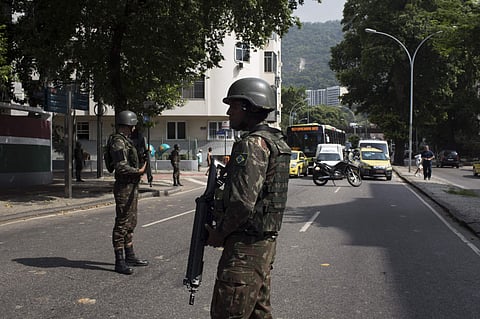 A soldier stops traffic for an armored vehicle to park on a street in Rio | AP