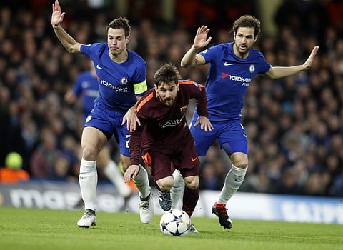 Barcelona's Lionel Messi, center, controls the ball as Chelsea's Cesar Azpilicueta, left, and his teammate Cesc Fabregas try to stop him during the Champions League, round of 16, first-leg soccer match at Stamford Bridge stadium. | AP