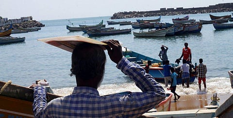 A file image of a fisherman looking at a group of young fishermen who are taking their boat into the sea at Vizhinjam.  (EPS | Kaviyoor Santhosh)