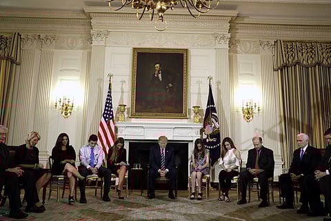 President Donald Trump bows his head during an opening prayer at the start of a listening session with high school students and teachers in the State Dining Room of the White House in Washington, Wednesday, Feb. 21, 2018. | AP
