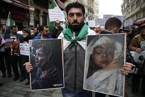 People holding pictures of victims of the airstrikes and shelling by Syrian government forces in Ghouta, a suburb of Damascus, Syria, gather during a rally outside the Russian Consulate in Istanbul. | AP