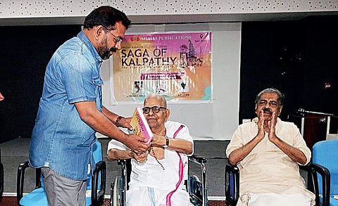 Poet Akkitham presents a copy of ‘Saga of Kalpathy - A Story of Palghat Iyers’ to Director of Public Education K V Mohan Kumar at the book launch in Kozhipara on Monday