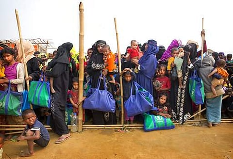 Rohingya Muslim women with their children stand in a queue outside a food distribution center. | AP
