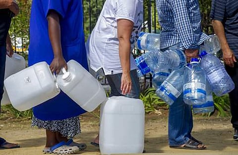 People queue to collect water from a natural spring outlet in the South African Breweries in Cape Town. | AP