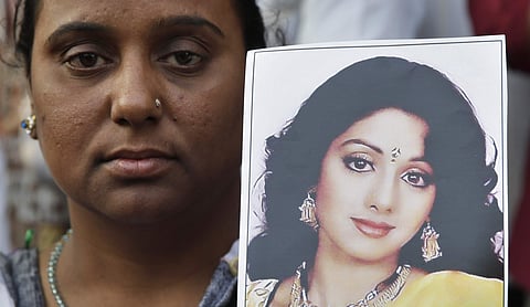 A fan of Bollywood actress Sridevi holds her photograph as she waits outside her residence to pay last respects in Mumbai.
