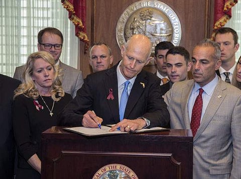 In this March 9, 2018 file photo, Florida Governor Rick Scott signs the Marjory Stoneman Douglas Public Safety Act in the governor's office at the Florida State Capitol in Tallahassee, Fla. Soon after Scott signed a school-safety bill that puts new restri