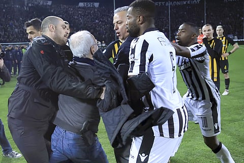 PAOK owner, businessman Ivan Savvidis, second from left, approaches AEK Athens' Manager Operation Department Vassilis Dimitriadis, center, as his bodyguard and PAOK's players Fernando Varela, second from right, and Djalma Campos, right, try to stop him du