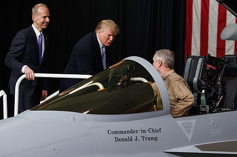 Boeing CEO Dennis Muilenburg listens as President Donald Trump talks with Boeing test pilot Steve Schmidt during a tour of fighter aircraft at the Boeing Company. | AP