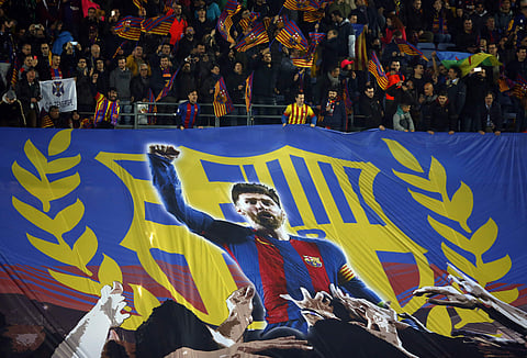 Barcelona supporters display a banner with a picture of Lionel Messi during the Champions League round of sixteen second leg soccer match against Chelsea. | AP