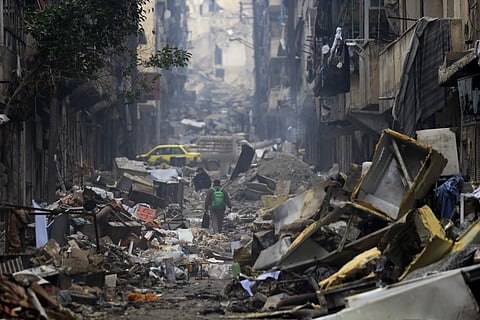 Residents walk through the rubble of the once rebel-held Salaheddine neighborhood in Syria. | AP