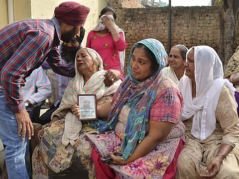 Family members grieve by a portrait of Harsimran Singh one of the 39 Indian workers whose bodies were found buried northwest of Mosul in Babowal village of Punjab on Tuesday.